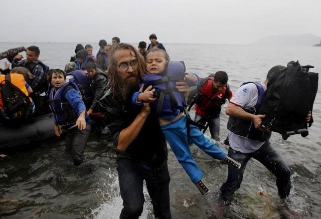 file photograph shows a volunteer carrying a syrian refugee child off an overcrowded dinghy at a beach after the migrants crossed part of the aegean sea from turkey to the greek island of lesbos september 23 2015 photo reuters