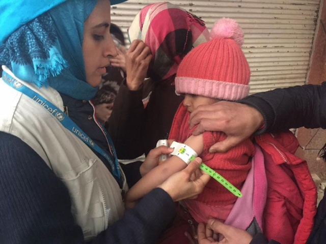 a unicef employee measures the arm of a malnourished child in the besieged syrian town of madaya on january 14 2016 photo afp