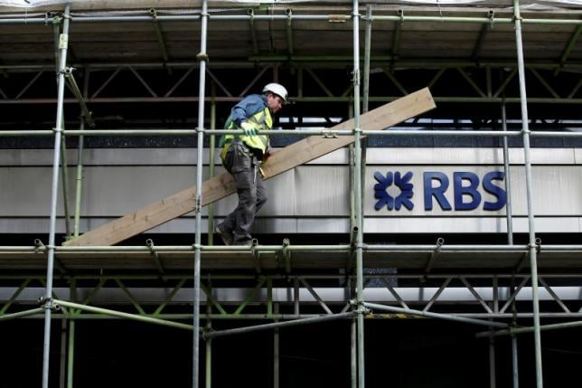 a scaffolder carries a plank past a sign for rbs on a building undergoing renovation in london march 21 2014 photo reuters