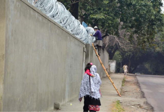 a worker erects barbed wires along the wall of a school photo mudassir raja express a worker erects barbed wires along the wall of a school photo mudassir raja express