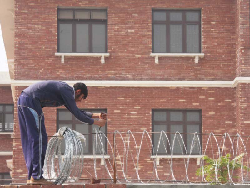 a staffer puts barbed wires on a boundary wall of islampura college photos abid nawaz express