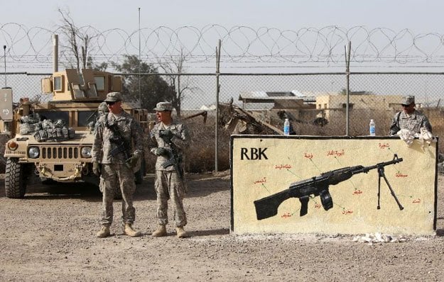 american and iraqi military trainers stand next to a painting of a rbk kalashnikov as they train iraqi soldiers at the taji base complex on january 7 2015 photo afp