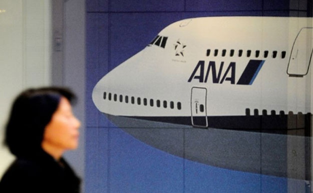 a woman walks past a picture showing a japan 039 s all nippon airways ana boeing 747 photo afp