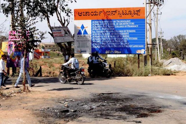 indian pedestrians walk past the spot where a vehicle was set ablaze by a mob in bangalore on feb 2 2016 photo afp