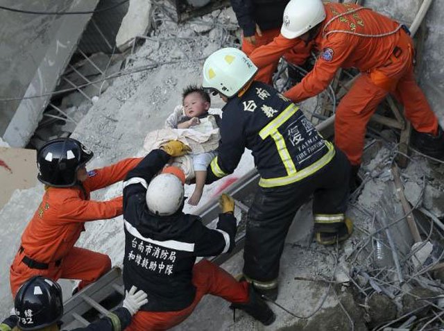 rescue personnel help a child rescued at the site where a 17 storey apartment building collapsed during an earthquake in tainan southern taiwan on february 6 2016 photo reuters