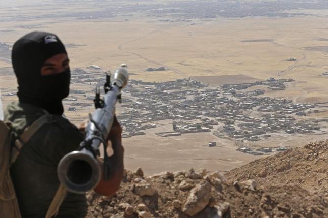 a kurdish peshmerga fighter holds a a rocket propelled grenade launcher as he takes up position in an area overlooking baretle village background which is controlled by the islamic state in khazir on the edge of mosul september 8 2014 photo reuters