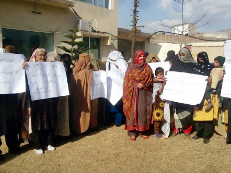 women hold banners and threaten to continue protest if demands not met photo express