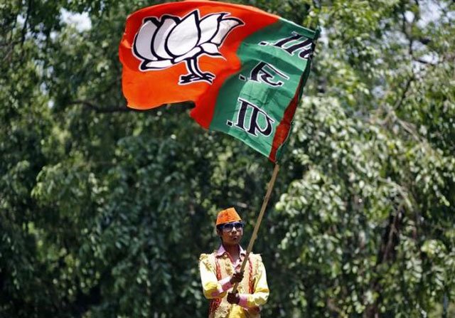 a supporter of bharatiya janata party bjp waves the party flag during celebrations after learning of initial poll results outside the party headquarters in new delhi may 16 2014 photo reuters