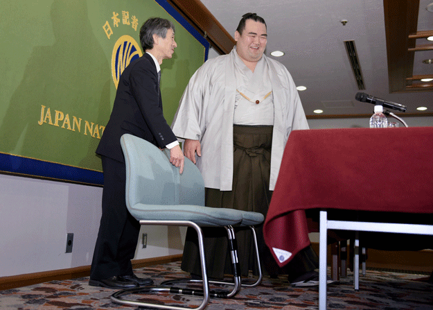 ozeki ranked or champion sumo wrestler kotoshogiku r is escorted to his seat    two chairs stuck together with packing tape    as he arrives to attend a press conference in tokyo on february 16 2016 photo afp