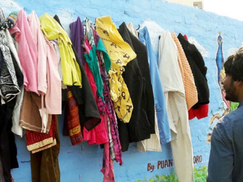 painted with the colours of the sky with a peacock gazing from a tree branch this wall of kindness on thandi sarak has been drilled with five sets of hooks to hang clothes for the poor and needy to grab photo courtesy huda bhurgari