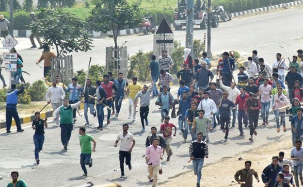 protesters run along a street during violent clashes with rival caste groups over access to jobs and education in rohtak northern india on february 19 2016 photo afp