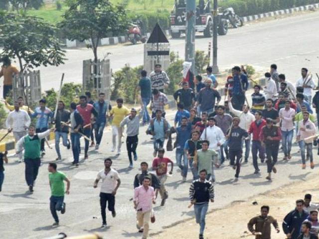 protesters run along a street during violent clashes with rival caste groups over access to jobs and education in rohtak northern india on february 19 2016 photo afp