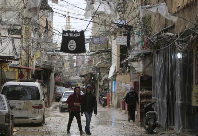 youth walk under an islamic state flag in ain al hilweh palestinian refugee camp near the port city of sidon southern lebanon january 19 2016 photo reuters