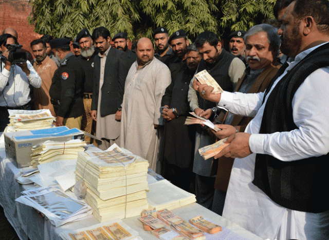 a police official displays fake currency notes next to men arrested during a raid on a factory making counterfeit money in lahore on february 25 2016 photo afp a police official displays fake currency notes next to men arrested during a raid on a factory making counterfeit money in lahore on february 25 2016 photo afp