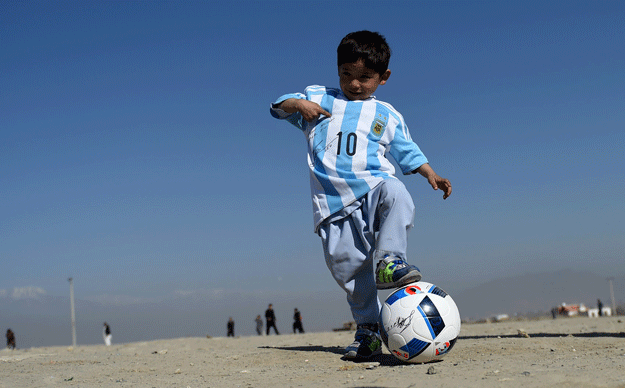 afghan boy five year old murtaza ahmadi plays football as he wears a donated and signed shirt by messi on a field in kabul on february 26 2016 photo afp