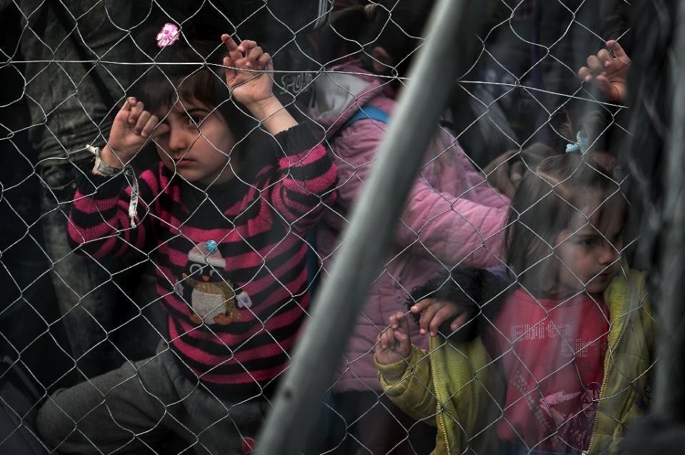 children behind a fence wait to cross the greek macedonian border along with other syrian and iraqis refugees near the village of idomeni on february 27 2016 photo afp