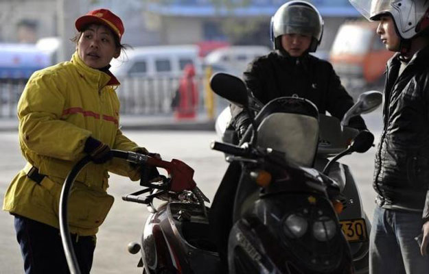 an employee fills a motorcycle tank as another motorcyclist waits to buy petrol at a gas station in hefei anhui province march 23 2012 reuters
