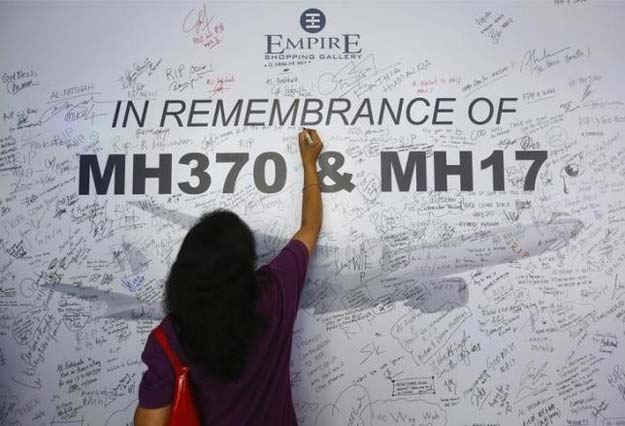 a woman writes a message on a dedication board for the victims of the downed malaysia airlines flight mh17 airliner and the missing flight mh370 in subang jaya outside kuala lumpur july 23 2014 reuters