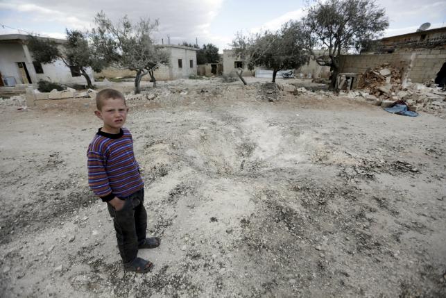 a boy stands near a hole in the ground after a shell fell in the rebel held town of jarjanaz southern idlib countryside syria march 5 2016 photo reuters