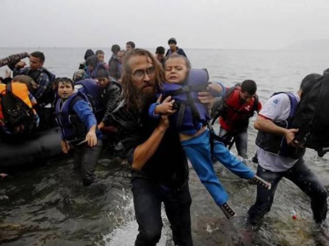 file photograph shows a volunteer carrying a syrian refugee child off an overcrowded dinghy at a beach after the migrants crossed part of the aegean sea from turkey to the greek island of lesbos september 23 2015 photo