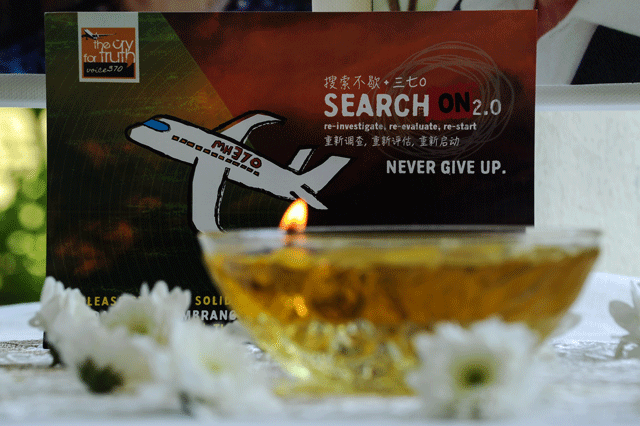 a candle burns a prayer message for passengers of missing malaysia airlines flight mh370 in petaling jaya on march 8 2016 photo afp