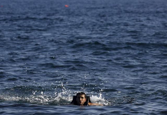 a man struggles as he approaches a beach on the greek island of lesbos after jumping from an overcrowded dinghy while crossing a part of the aegean sea from turkey september 17 2015 reuters