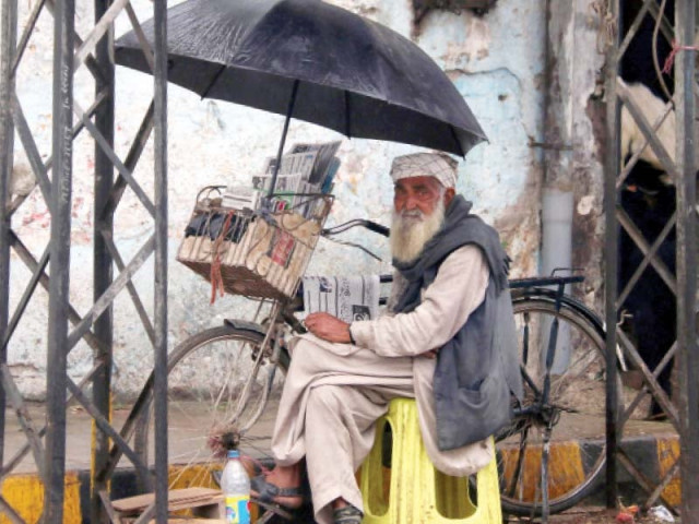a man sits under an umbrella during rains in the city photo muhammad iqbal express a man sits under an umbrella during rains in the city photo muhammad iqbal express
