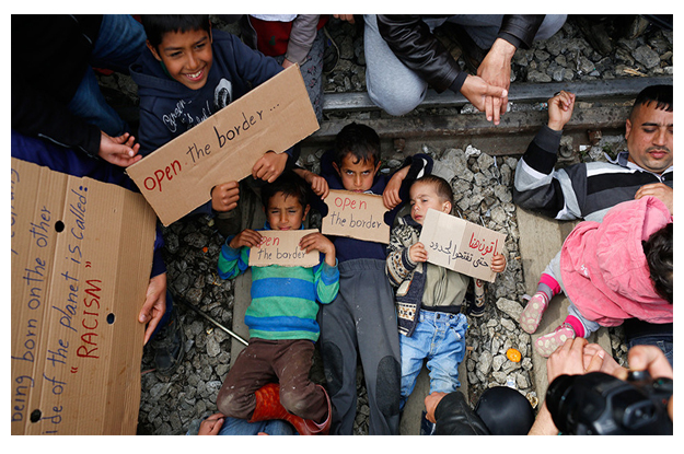 migrants hold posters as they block the railway track at the greek macedonian border near the village of idomeni greece march 12 2016 photo reuters