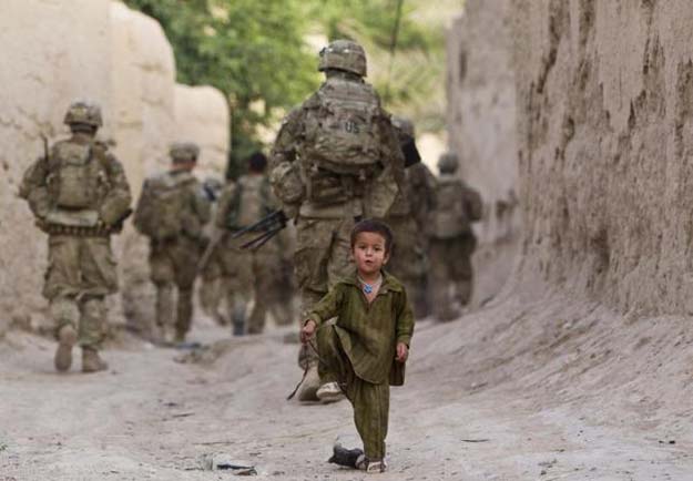 a boy plays on a street as us army soldiers of the battle company 1 508 parachute infantry battalion 4th brigade combat team 82nd airborne division patrol during a mission in zahri district of kandahar province southern afghanistan may 30 2012 reuters