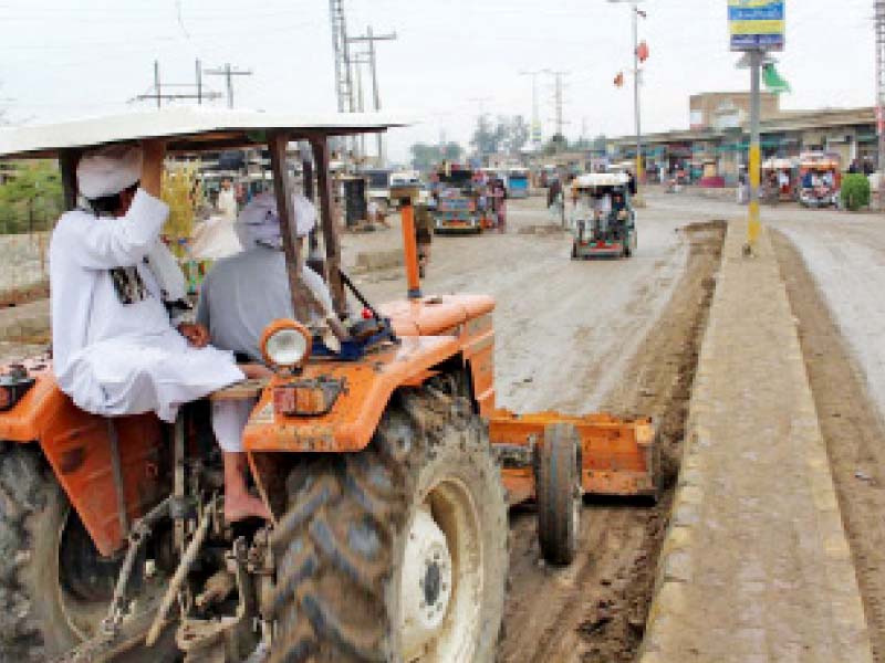 tank naib nazim cleaning a road with the help of a tractor photo express