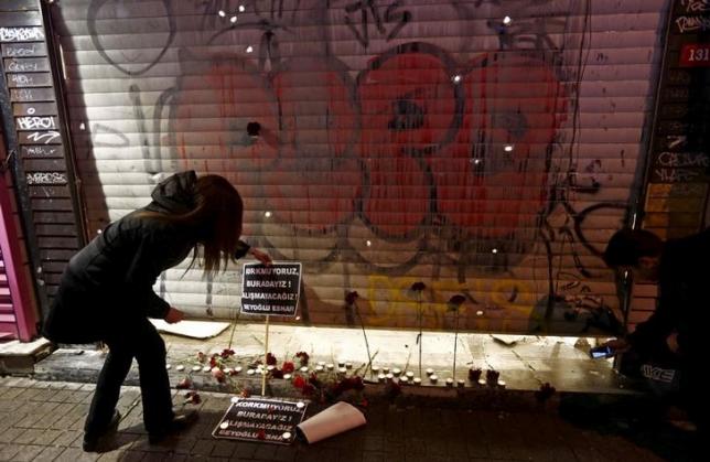 a woman places carnations and a sign at the scene of a suicide bombing at istiklal street a major shopping and tourist district in central istanbul turkey march 19 2016 the signs read quot we are not afraid we are here we will not get used to it beyoglu district shopkeepers quot photo reuters