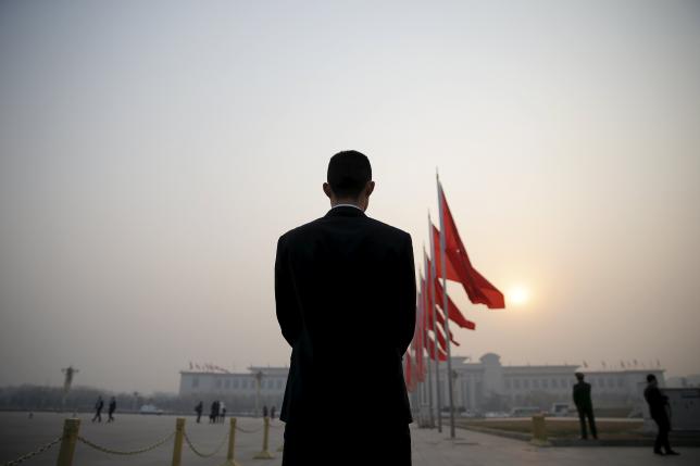 a security agent stands guard near the great hall of the people as the sun appears through smog ahead of the closing ceremony of china 039 s national people 039 s congress npc in beijing china march 16 2016 photo reuters