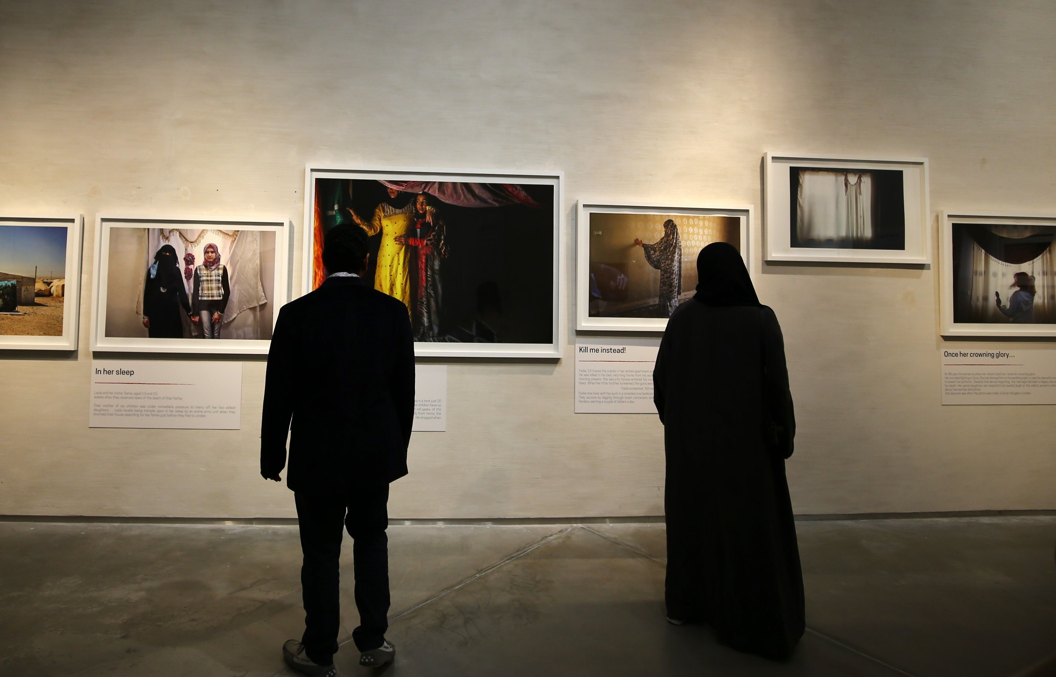 visitors look at images taken by jordanian photographer tanya habjouqa of syrian refugees during a joint exhibition along with syrian artist omar imam on refugees and migrants fleeing war and poverty on march 10 2016 in dubai the exhibition also pays tribute to photographer leila alaoui who was among dozens killed in a january attack claimed by al qaeda on a hotel in burkina faso photo afp