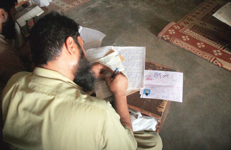 an inmate writes answers on his sheets while giving his secondary education exams at the central jail karachi on saturday photo athar khan express