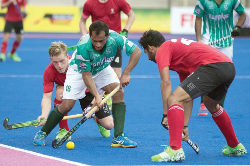 rashid mehmood tries to keep the ball as two canadians close in on him during pakistan s clash against canada in the opening match photo courtesy field hockey canada