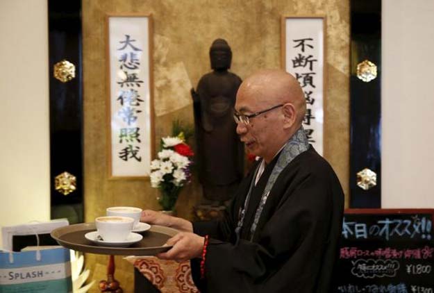 shokyo miura a buddhist monk and one of the on site priests carries cups of coffee past a statue of buddha at tera cafe in tokyo japan april 1 2016 photo reuters