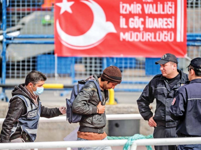a police officer escorts a migrant from a turkish ferry photo afp a police officer escorts a migrant from a turkish ferry photo afp