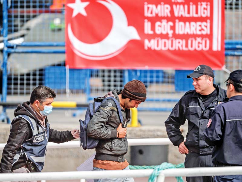 a police officer escorts a migrant from a turkish ferry photo afp