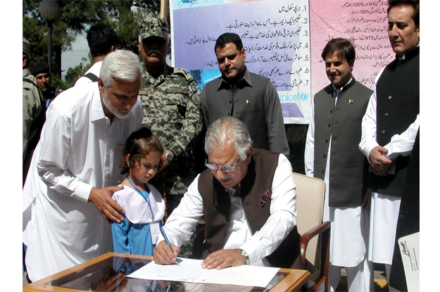 governor iqbal zafar jhagra signing the enrollment form of a child at agency headquarter khar photo inp