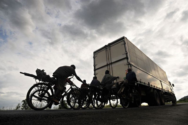 bicycle transporters hang onto the back of a truck riding in burundi 039 s capital bujumbura photo afp