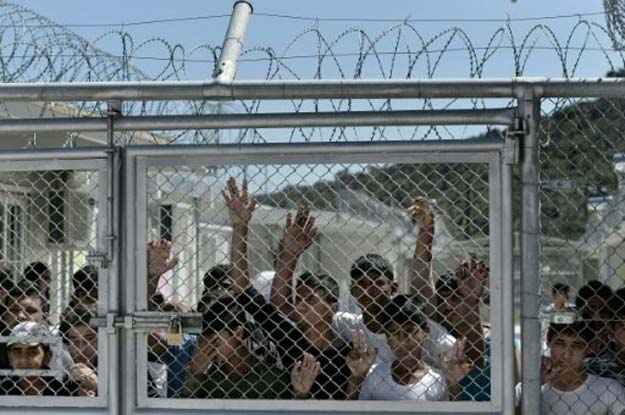 young migrants and refugees at a fence in the moria detention center on the greek island of lesbos on april 16 2016 photo afp