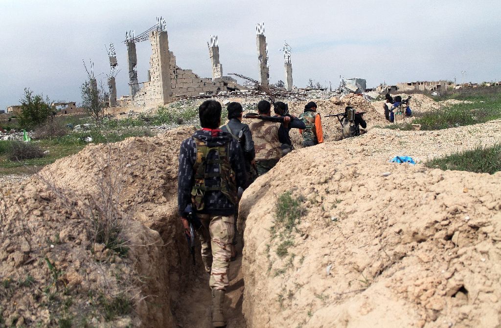 rebel fighters walk along a trench in the northeastern syrian city of deir ezzor during fighting with pro regime fighters on march 24 2014 photo afp