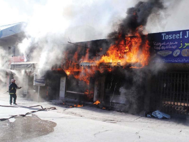 a firefighter tries to extinguish the blaze at the jewellery shop in rawalpindi photo nni a firefighter tries to extinguish the blaze at the jewellery shop in rawalpindi photo nni