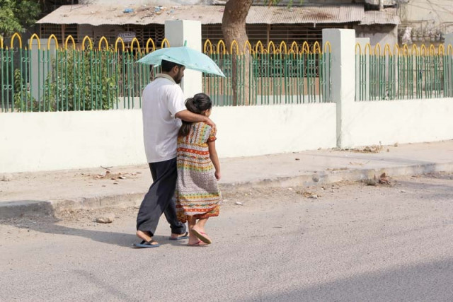 a man escorts a child to school carrying an umbrella to protect themselves from the heat photo file a man escorts a child to school carrying an umbrella to protect themselves from the heat photo file