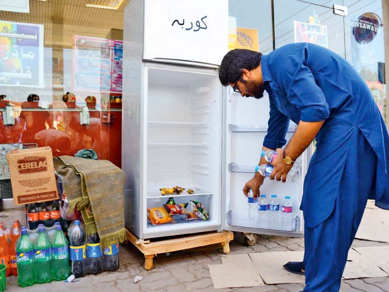 a man arranges food items in a refrigerator photo express