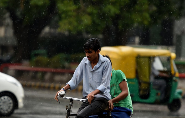 an indian cyclist makes his way during a rain shower in new delhi on may 23 2016 afp photo an indian cyclist makes his way during a rain shower in new delhi on may 23 2016 afp photo