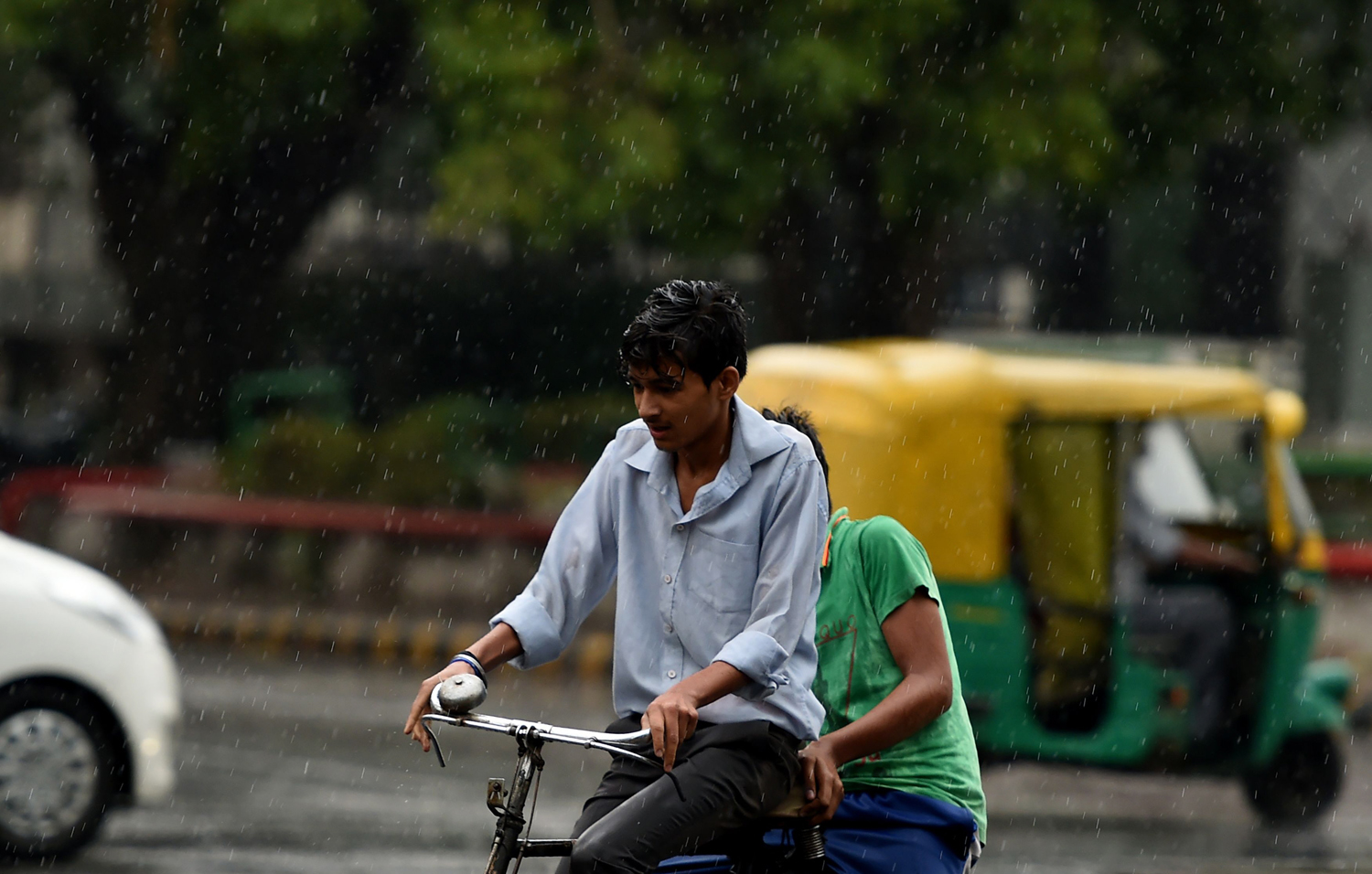 an indian cyclist makes his way during a rain shower in new delhi on may 23 2016 afp photo