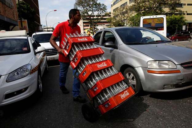 a worker pushes a dolly loaded with cases of empty coca cola bottles in caracas venezuela may 24 2016 photo reuters