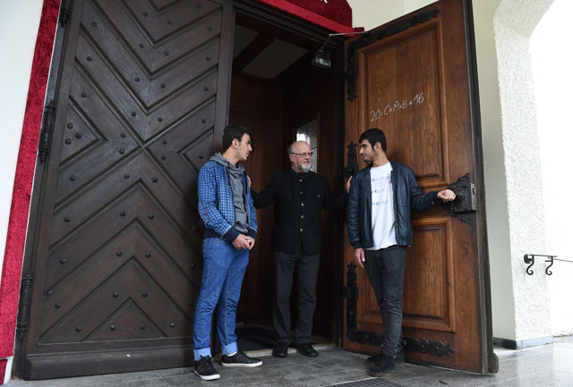pastor peter brummer c speaks with the iraqi immigrants peshtiwan nasser abdal l and suud iazdxn arab r in front of the sant joseph church in tutzing southern germany on may 24 2016 photo afp