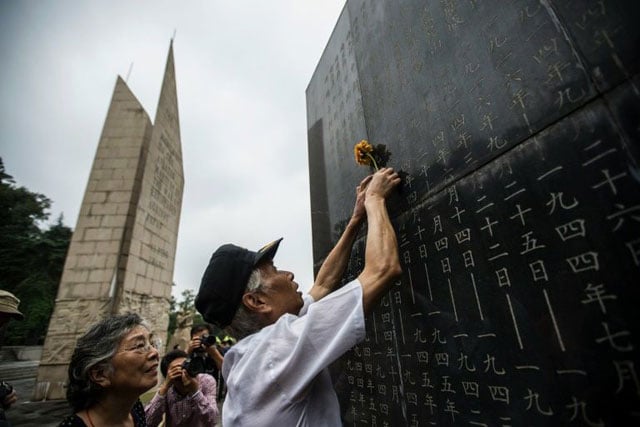 a man places a flower on a monument in nanjing showing the names of people who died in battles against japan during world war ii photo afp